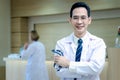 Portrait of friendly smiling senior Asian male doctor in workwear with stethoscope, standing with arms crossed in clinic hospital Royalty Free Stock Photo