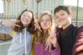 Portrait of friends teen boy and two girls smiling, making funny faces, showing victory sign in the street Royalty Free Stock Photo