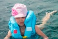 Portrait of a frightened child in the sea. A baby is saved after a disaster. A sad little girl in a life jacket tries to swim in