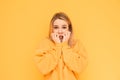 Portrait of a frightened girl on a yellow background looks shocked at the camera and bites her fingers. Isolated. Girl with light Royalty Free Stock Photo