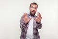 Portrait of frightened shocked bearded man standing with scared eyes and arms raised trying to defend himself. white background