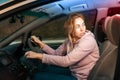 Portrait of a frightened young Caucasian woman driving a right-handed car, looking back at the police siren light