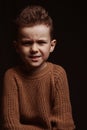 Portrait of frowning serious angry stylish white Caucasian child boy kid preschooler on a chair