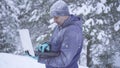 Portrait frozen man in winter forest uses laptop