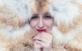 Portrait of a frozen young girl in a fox fur coat, warm her hands, cold, snow, frost, blizzard Royalty Free Stock Photo