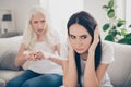 Portrait of frustrated angry young girl have disagreement misunderstanding with her old irritated mother sit couch tell Royalty Free Stock Photo