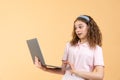 Portrait of frustrated computer user, teen girl with curly brunette hair in pink shirt looking at laptop, worried about Royalty Free Stock Photo