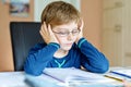 Portrait of frustrated crying sad school kid boy at home making homework. Little child writing with colorful pencils Royalty Free Stock Photo