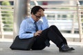 Portrait of frustrated stressed young Asian man sitting on the floor of sidewalk office and feeling tired with job Royalty Free Stock Photo