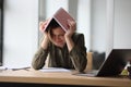 Frustrated woman covering head with book feeling tired and powerless