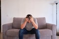 Portrait of a frustrated young man sitting on a sofa with his hands on his head