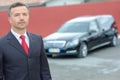 Portrait funeral director standing in front hearse