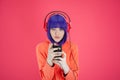 Portrait funky beautiful young woman with blue hair in hoodie on bright pink background. Alternative girl with headphone