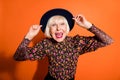 Portrait of funky crazy good mood happy positive grandmother smiling hold headwear isolated on orange color background Royalty Free Stock Photo