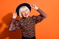 Portrait of funky positive good mood happy old woman wear headwear smiling on camera on orange color background