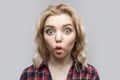 Portrait of funny amazed beautiful blonde young woman in casual red checkered shirt standing and looking at camera with big eyes Royalty Free Stock Photo