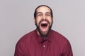 Portrait of funny amazed man with dark hair and beard in red shirt standing and looking at camera with big open mouth and Royalty Free Stock Photo