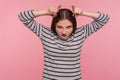 Portrait of funny angry woman in striped sweatshirt showing bull horn gesture and looking with hate rage Royalty Free Stock Photo