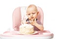 Portrait Of Funny Baby eating cake by hands and smiling while sitting in high chair. Self feeding concept. Isolated on white Royalty Free Stock Photo