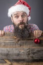 Portrait of a funny bearded man with santa cap holding a red round Christmas ball Royalty Free Stock Photo