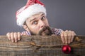 Portrait of a funny bearded man with santa cap holding a red round Christmas ball Royalty Free Stock Photo