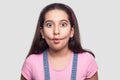 Portrait of funny beautiful brunette young girl in casual pink t-shirt and blue overalls standing and looking at camera with fish Royalty Free Stock Photo