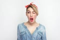 Portrait of funny beautiful young woman in casual blue denim shirt with makeup and red headband standing winking and looking at