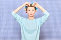 Funny focused young woman is putting her hair into colorful curlers Royalty Free Stock Photo