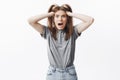 Portrait of funny caucasian brunette girl in grey clothes holding hair with hands, looking in camera with opened mouth Royalty Free Stock Photo