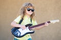 Portrait of a funny child with glasses practicing a song during a guitar lesson on street. Music concept, kids music Royalty Free Stock Photo