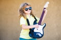 Portrait of a funny child with glasses practicing a song during a guitar lesson on street. Music concept, kids music Royalty Free Stock Photo