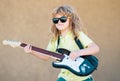 Portrait of a funny child with glasses practicing a song during a guitar lesson on street. Music concept, kids music Royalty Free Stock Photo