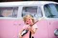 Portrait of a funny child with pink glasses practicing a song during a guitar lesson on street. Music concept, kids