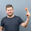 Portrait of funny chubby man in shock while talking on phone having unpleasant conversation against gray background Royalty Free Stock Photo