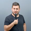 Portrait of funny chubby man singer against gray background