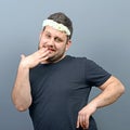 Portrait of funny chubby man wearing flower wreath on head and behaving feminine against gray background