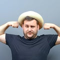 Portrait of funny chubby man wearing straw hat showing muscles