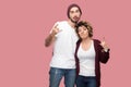 Portrait of funny couple of friends in casual style standing, hugging each other and showing rock and roll hand sign gesture, Royalty Free Stock Photo