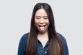 Portrait of funny crazy beautiful brunette asian young woman in casual blue denim jacket with makeup standing with closed eyes and Royalty Free Stock Photo