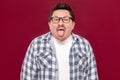 Portrait of funny crazy handsome middle aged business man in casual checkered shirt and eyeglasses standing, tongue out and Royalty Free Stock Photo