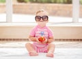 Portrait of funny cute white Caucasian smiling baby girl wearing large sunglasses sitting on floor in swimming pool Royalty Free Stock Photo