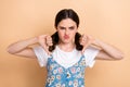 Portrait of funny dissatisfied woman ponytails hairdo dressed white shirt showing thumbs down dislike isolated on beige Royalty Free Stock Photo