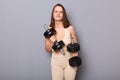 Portrait of funny dissatisfied young woman wearing sportswear holding dumbbells making weightlifting, frowning face, having hard Royalty Free Stock Photo