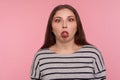 Portrait of funny dumb amusing woman in striped sweatshirt standing with crossed eyes, showing tongue out