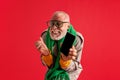 Portrait of funny elderly man with beard looking at camera clenching his hand into fist and holding phone with blank Royalty Free Stock Photo