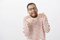 Portrait of funny emotive man in glasses making faces and mimicking dinosaur paws with hands over chest, yelling or Royalty Free Stock Photo