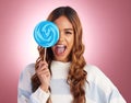 Portrait, funny face and giant lollipop with a woman in studio on a pink background holding candy. Comic, comedy and