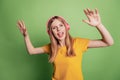 Portrait of funny funky hipster dj lady listen music dance party wear earphones yellow t-shirt on green background