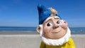 Portrait of a funny garden gnome in front of the beach