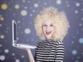 Portrait of funny girl in blonde wig with laptop. Royalty Free Stock Photo